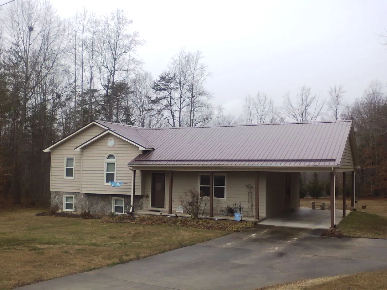 Burgundy metal roof on a tan split level home with an attached carport in Pigeon Forge