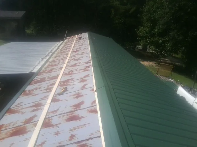 Old rusted panels beside newly installed green metal roofing — Wind Damage Roof Repair by Roofing Brothers in Pigeon Forge