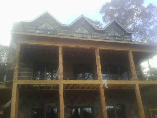 Dormers and porch framing on a large log home under construction — Roof Coating work by our crew in Pigeon Forge