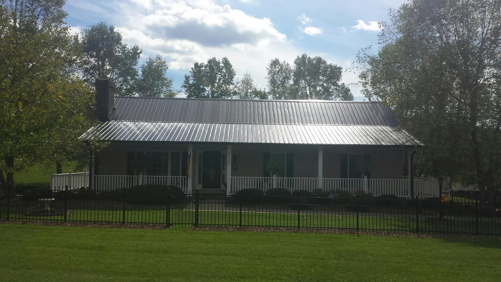 Gray metal roof on a brick ranch with a full width front porch — Gutter Guard Installation work by our crew in Pigeon Forge