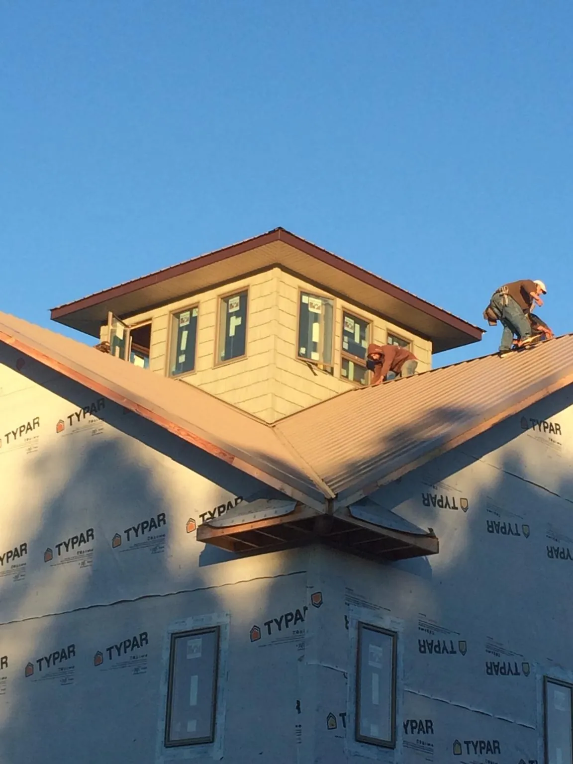 Roofers working around a rooftop cupola on a new metal roof at sunset — Roof Waterproofing in Pigeon Forge by Roofing Brothers